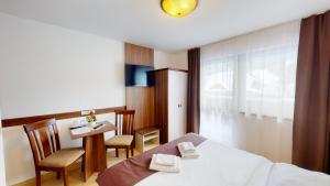 Habitación de hotel con cama, mesa y sillas en Garni Hotel Fatra, en Terchová