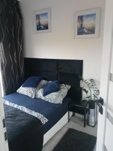 a bed with a black headboard in a bedroom at AL Mare Apartament in Gdańsk
