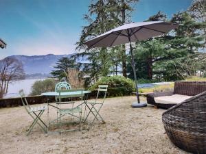 un tavolo con sedie con ombrellone e divano di La Bohême du Lac a Le Bourget-du-Lac