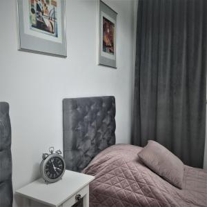 1 dormitorio con 1 cama y reloj sobre una mesa en Oliwa Am Calsberg 5a, en Gdansk