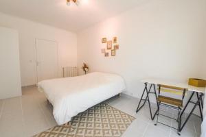 Habitación blanca con cama y escritorio en charmant logement plein pied au cœur du village, en Castelculier