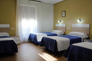 a room with three beds with blue and white sheets at Hostal Madrid in Toledo