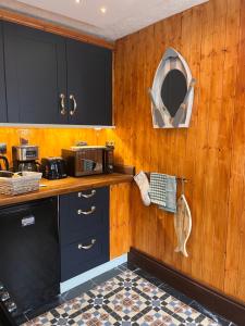 a kitchen with wood paneling and a counter with a microwave at Harbour View Ground Floor Flat with Private Parking, only 5 Mins walk to harbour in Brixham