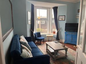 a living room with a blue couch and a table at Harbour View Ground Floor Flat with Private Parking, only 5 Mins walk to harbour in Brixham