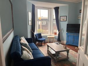 布里克瑟姆Harbour View Ground Floor Flat with Private Parking, only 5 Mins walk to harbour的客厅里有一张蓝色的沙发和一张桌子