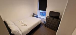 a bedroom with a bed and a dresser with a television at SELF CHECK IN APARTMENT DONCASTER in Doncaster