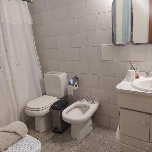 a white bathroom with a toilet and a sink at La Glicina casa in La Plata