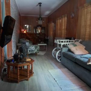 sala de estar con sofá, mesa y TV en La Glicina casa en La Plata