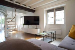 ein Wohnzimmer mit einem Sofa und einem Tisch in der Unterkunft Duplex de charme avec terrasse aux portes de Paris in Saint-Germain-en-Laye