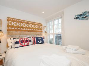 a bedroom with a white bed with a wooden headboard at Salty Sea Dog in Tintagel