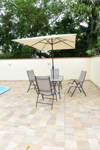 una mesa y sillas con una sombrilla en el patio en Beto Carreiro - Praia - Relaxar à beira da piscina ou prepara algo na churrasqueira - Aproveite o seu tempo livre com a família e amigos em nosso espaço en Piçarras
