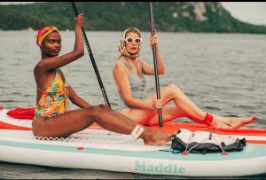 dos mujeres sentadas en una tabla de paddle en el agua en THE SHORELINE CABIN en Kodiak