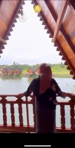 a woman standing on a balcony looking at the water at Resort & Resto Talaga Sundayana in Subang