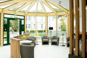 une véranda avec des chaises, des tables et des fenêtres dans l'établissement Garni Eden Hotels, à Ahlbeck