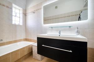 y baño con lavabo, bañera y espejo. en Sea & Mountain Apartment en Lávrion