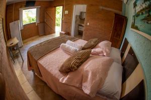 a bedroom with a large bed with two pillows at Chalés Sapucaí Pousada in São Bento do Sapucaí