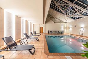 una piscina en una habitación con sillas y mesas en Parador De La Seu D'urgell, en La Seu d'Urgell