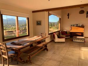 a room with a table and windows and a piano at Espectacular casa en Trevelin. in Trevelin +23 photos