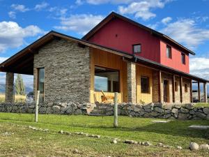 a house with a red roof and a stone wall at Espectacular casa en Trevelin. in Trevelin