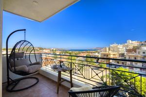 een balkon met een schommelstoel en uitzicht op de stad bij Sea & Mountain Apartment in Lávrion