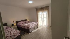 - une chambre avec 2 lits et une grande fenêtre dans l'établissement Apartmani Juresko Mrljane, à Mrljane