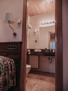 a bathroom with a sink and a toilet and a mirror at Hostal Les Fonts in Castellar de NʼHug