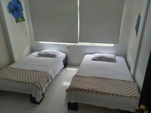 two beds in a small room with a window at Hotel Avei Suites in Cali