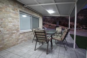 eine Terrasse mit einem Tisch, Stühlen und einer Ziegelwand in der Unterkunft סוויטות נופי החרמון - Hermon View Suites in Madschdal Schams
