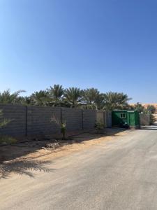 a road with a fence and a green building at مزرعة السلطانية in Buraydah