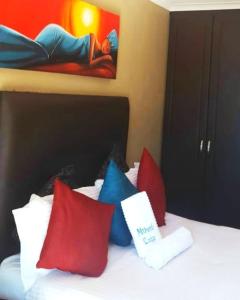 um quarto com uma cama com almofadas vermelhas e azuis em Mthandi Wokuhamba Lodge em Dundee