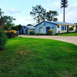a blue house with a green lawn in front of it at Mthandi Wokuhamba Lodge in Dundee +8 photos