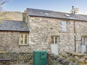 een stenen huisje met een picknicktafel ervoor bij Oaktree Cottage-uk42227 in Low Borrowbridge