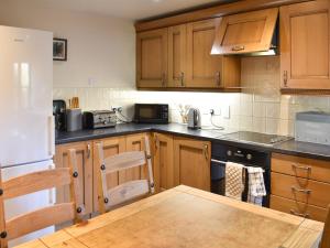 een keuken met houten kasten en een houten tafel. bij Oaktree Cottage-uk42227 in Low Borrowbridge