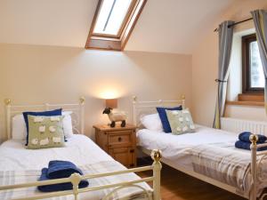 twee bedden in een kamer met twee ramen bij Oaktree Cottage-uk42227 in Low Borrowbridge