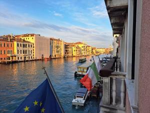 威尼斯的住宿－西娜聖天使宮殿酒店，从带旗帜的建筑中欣赏到运河的景色