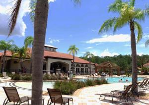 a pool at a resort with chairs and palm trees at Four Bedrooms Townhouse 4563 in Kissimmee