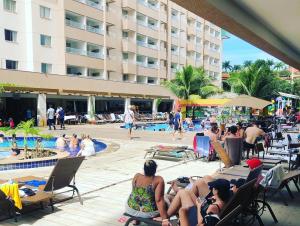 um grupo de pessoas sentadas em torno de uma piscina em um hotel em Apartamento em Resort de Olimpia em Olímpia