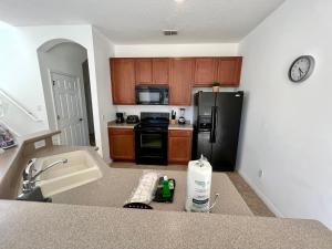 a kitchen with a black refrigerator and a sink at Four Bedroom w/ Screened Pool Close to Disney 4572 in Kissimmee