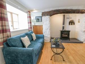 uma sala de estar com um sofá azul e um fogão a lenha em Happy Landing em Harlech