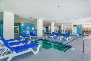 a swimming pool with blue chairs in a building at Ocean Blue - Ocean View Condos by Coastline Resorts in Myrtle Beach