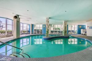 a large swimming pool in a building with glass windows at Ocean Blue - Ocean View Condos by Coastline Resorts in Myrtle Beach