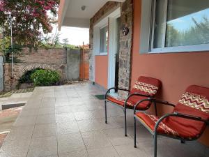 dwa czerwone krzesła siedzące na ganku obok budynku w obiekcie Los Zorzales w mieście Villa Carlos Paz