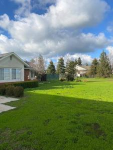 a yard with a house and a green lawn at Beautiful peaceful desirable home in Madera Rancho in Madera