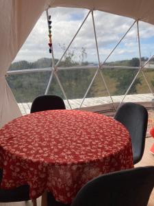 een rode tafel in een tent met stoelen en een raam bij Domo con tinaja, Estaquilla in Los Muermos