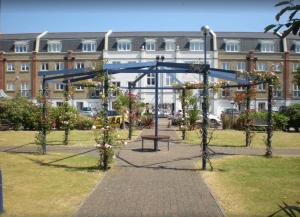 un parque con un banco frente a un edificio en Fabulously located Marina apartment - marina views, en Pevensey