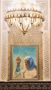 ein Gemälde einer Nonne an einer Wand mit einem Kronleuchter in der Unterkunft Riad Amelia : Lalla Nora Room in Tétouan