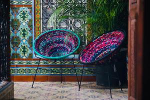 two colorful chairs sitting next to a wall at Riad Amelia : Lalla Nora Room in Tetouan