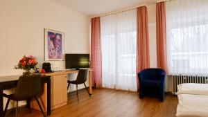 a room with a desk with a computer and two chairs at Hotel Pegasus in Munich