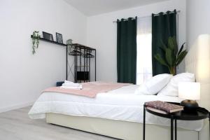 Schlafzimmer mit einem großen weißen Bett und grünen Vorhängen in der Unterkunft The Libra Nordic Home in Rom