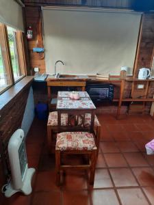 cocina con mesa, sillas y fregadero en Cabaña La iluminada en Tandil